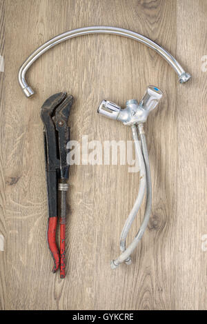 Rusty old plumbing wrench and tap on wooden background Stock Photo