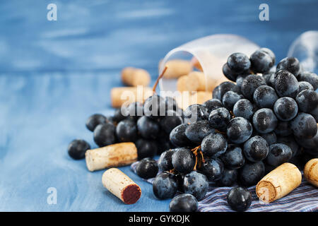 Branch of purple grape and wine corks on the table with glass and bottle on background Stock Photo