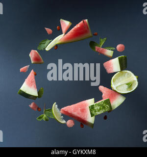 Slices of flying ripe juicy organic watermelon isolated on black , served with fresh lime and mint leaves. Watermelon mojito ing Stock Photo