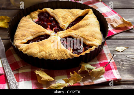 Homemade cherry and apple pie over rustic wooden background with yellow leaves, copy space - delicious autumn pastry Stock Photo