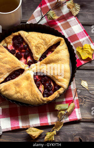 Homemade cherry and apple pie over rustic wooden background with yellow leaves - delicious autumn pastry Stock Photo