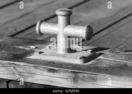 Black and white square photo with mooring bollard mounted on wooden pier, port equipment Stock Photo