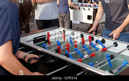 Unrecognizable people enjoying a game of table soccer. No faces shown. Stock Photo