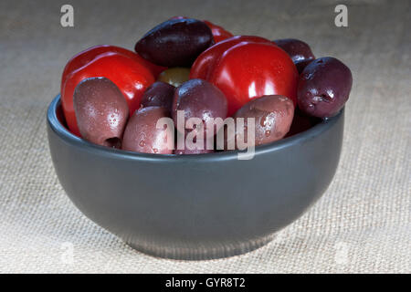 tomatoes and olives in a black bowl on the table Stock Photo