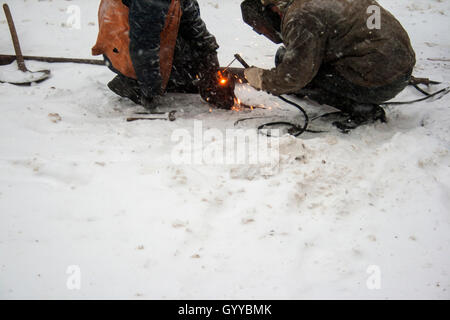 Welders working on snow during a snowfall Stock Photo