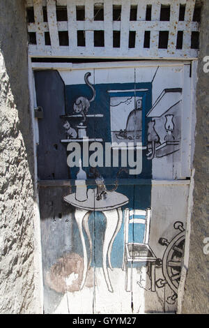 old wooden door decorated with a painting of house whith cats in the old city of Amantea. Stock Photo