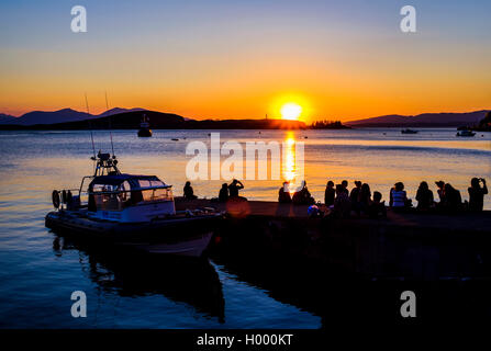 Silhouette of young people in the water, watching the sunset, Oban, Argyll and Bute, Scotland, United Kingdom Stock Photo