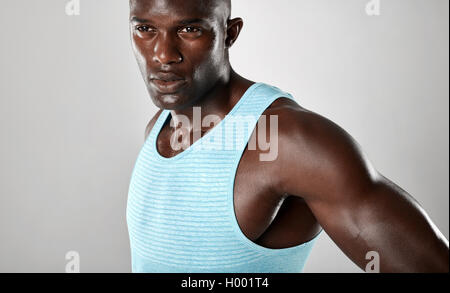 Close up shot of confident young african man with muscular build looking away over grey background. Stock Photo