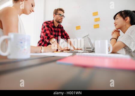 Group of startup executives discussing new business ideas during a meeting in modern workplace. Employees meeting around a table Stock Photo