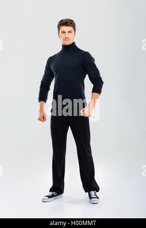 Full length of handsome strong young man in black clothes standing Stock Photo
