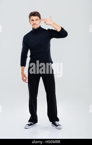 Full length of irritated young man standing with fingers to temple like a gun Stock Photo