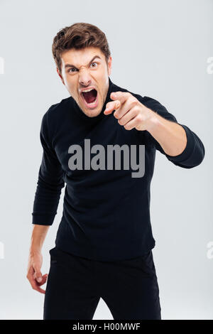 Mad furious young man pointing on you and shouting Stock Photo