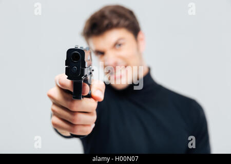 Closeup of angry young man pointing with gun on you Stock Photo