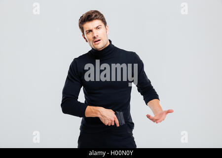 Irritated young man standing and posing with gun Stock Photo