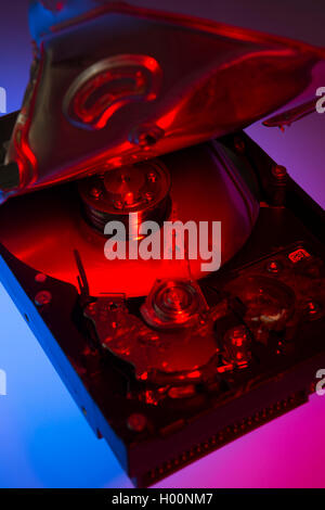 A broken computer hard drive with casing cracked open and disc visible inside. Stock Photo