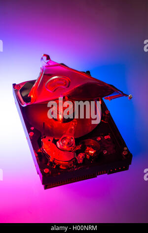 A broken computer hard drive with casing cracked open and disc visible inside. Stock Photo