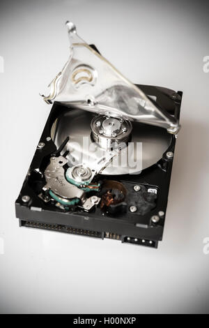 A broken computer hard drive with casing cracked open and disc visible inside. Stock Photo