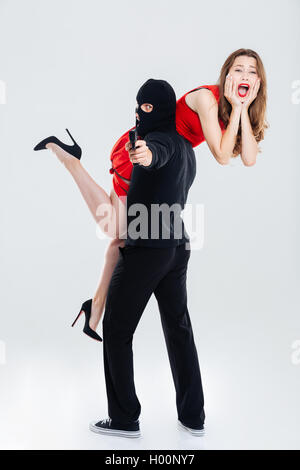 Man in balaclava stealing young woman and pointing gun on you Stock Photo
