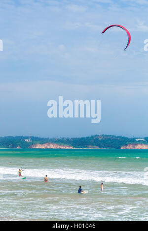 WELIGAMA, SRI LANKA - MARCH 7, 2014: Tourists swimming and kitesurfing in the sea. Tourism and fishing are two main business in Stock Photo