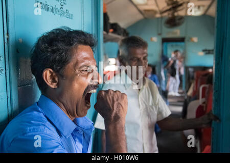 HIKKADUWA, SRI LANKA - MARCH 12, 2014: Local man yawning in train. Trains are very cheap and poorly maintained but it's the best Stock Photo