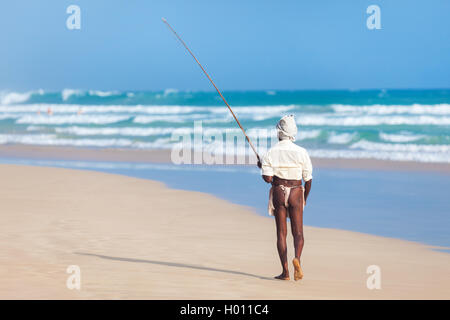 UNAWATUNA, SRI LANKA - MARCH 9, 2014: Elderly stilt fisherman walks at Hikkaduwa Beach. Most real stilt fishermen have been long Stock Photo