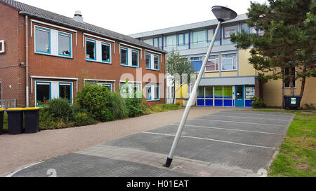 knocked down street lamp on a parking place in front of a school building, Netherlands Stock Photo