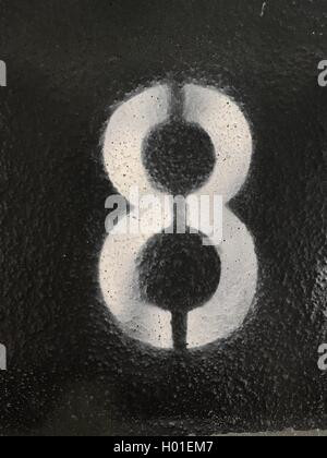 White Number 8 painted in stencil style on a the ground or wall Stock Photo