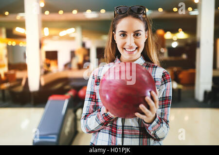 Woman throwing bowling ball in club Stock Photo