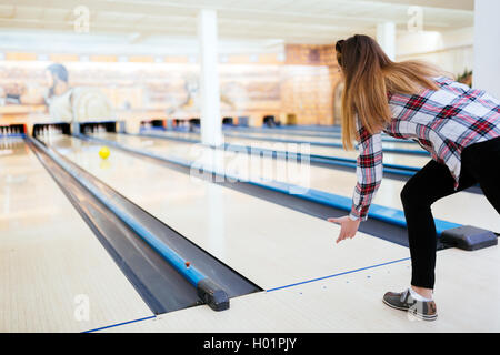 Woman throwing bowling ball in club Stock Photo