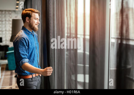 Handsome man looking at cityscape through skyscraper window Stock Photo