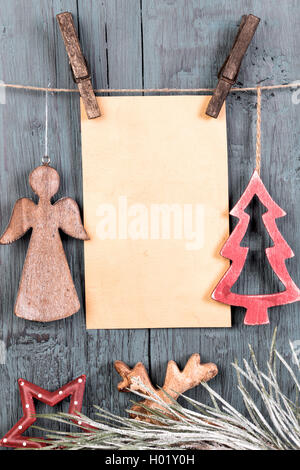 Decorations in the shape of Christmas tree and angel and blank greetings card hanging on string on old background Stock Photo