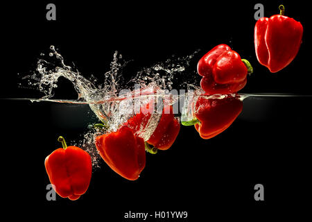 Group of bell pepper falling in water on black Stock Photo