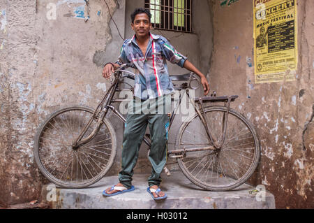VARANASI, INDIA - 25 FEBRUARY 2015: Indian boy stands next to traditional bicycle part in corner of street. Stock Photo