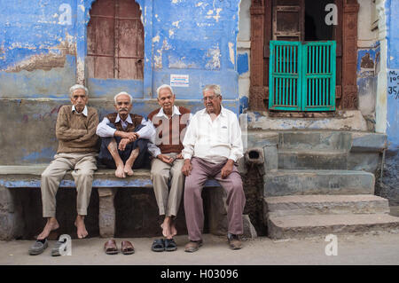 JODHPUR, INDIA - 16 FEBRUARY 2015: Four elderly men sit on stone bench on street infront of house. Stock Photo