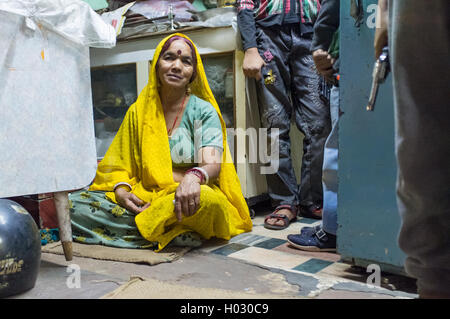 JODHPUR, INDIA - 16 FEBRUARY 2015: Woman sitting on floor of store while children stand next to her holding toy guns. Stock Photo