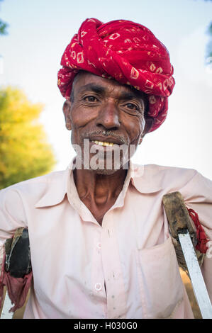 GODWAR REGION, INDIA - 12 FEBRUARY 2015: Rabari tribesman in field with crutches. Rabari or Rewari are an Indian community in th Stock Photo