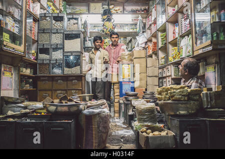 JODHPUR, INDIA - 10 FEBRUARY 2015: Three men in various merchandise store talk business. Post-processed with grain and texture. Stock Photo