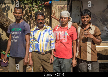 MUMBAI, INDIA - 09 JANUARY 2015: Three Indian adults stand with construction manager with glasses in street. Man with chai in ha Stock Photo