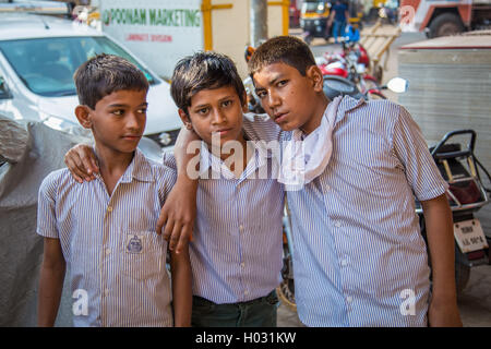 MUMBAI, INDIA - 16 JANUARY 2015: Three young boys in school uniforms stand in street together with hands on each others shoulder Stock Photo