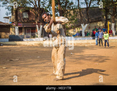 MUMBAI, INDIA - 16 JANUARY 2015: Adult Indian man hits ball with wooden cricket bat on school playground. Stock Photo