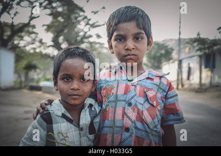 HAMPI, INDIA - 31 JANUARY 2015: Two Indian boys hug in street. Post-processed with grain, texture and colour effect. Stock Photo