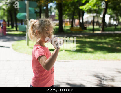 Little girl with bottle of mineral water, summer outdoor Stock Photo