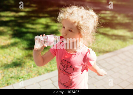 Little girl with bottle of mineral water, summer outdoor Stock Photo