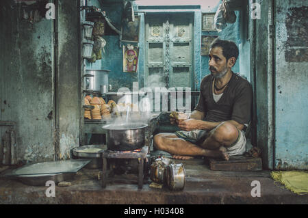 VARANASI, INDIA - 25 FEBRUARY 2015: Indian man counts money in street shop after whole day selling milky tea. Post-processed wit Stock Photo
