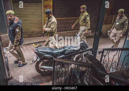 VARANASI, INDIA - 20 FEBRUARY 2015: Four Indian policemen walk on street of old part of Varanasi and pass by parked motorcycle. Stock Photo