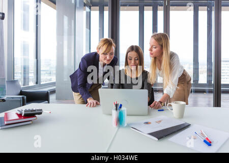 Three business women in modern office working on the project together. Stock Photo