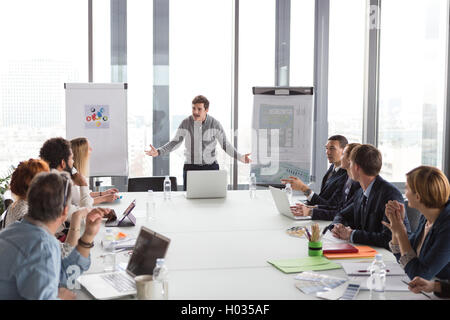 Hipster business man holding coffee cup and presenting the project in modern office. Stock Photo