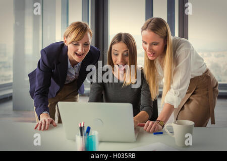 Three business women in modern office working on the project together. Post processed with vintage film filter. Stock Photo