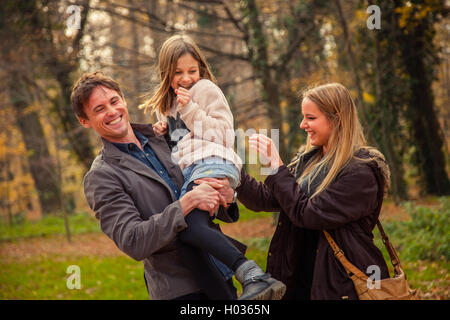 Playfull family of three walk in a park on an autumn day. Stock Photo