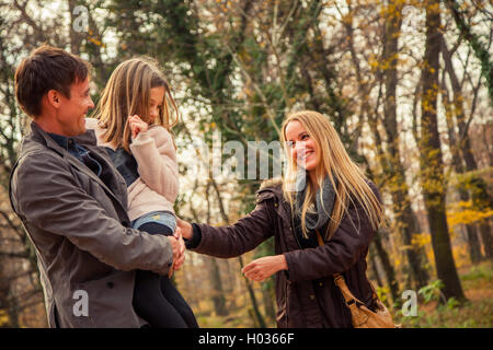 Playfull family of three walk in a park on an autumn day. Stock Photo